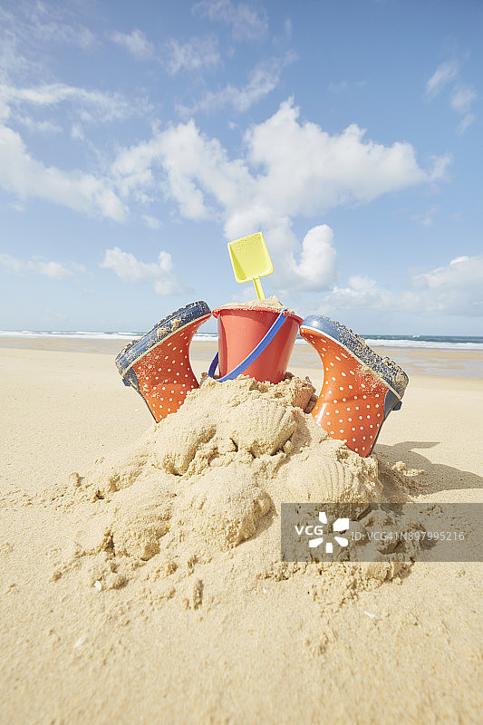 在欧洲法国的海滩上，用胶靴、砂桶和铲子建造的沙堡图片素材
