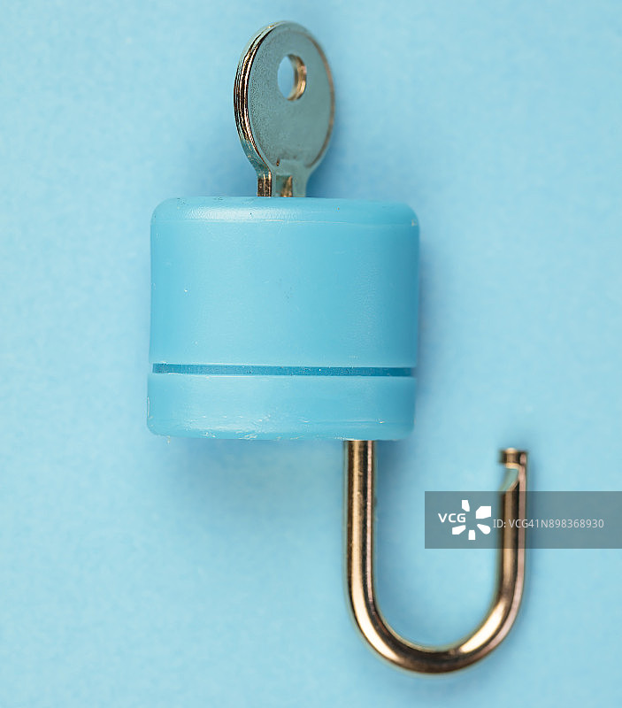 蓝色挂锁，钥匙在蓝色背景上图片素材