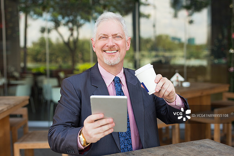 快乐的商业领袖在街头咖啡馆使用平板电脑图片素材