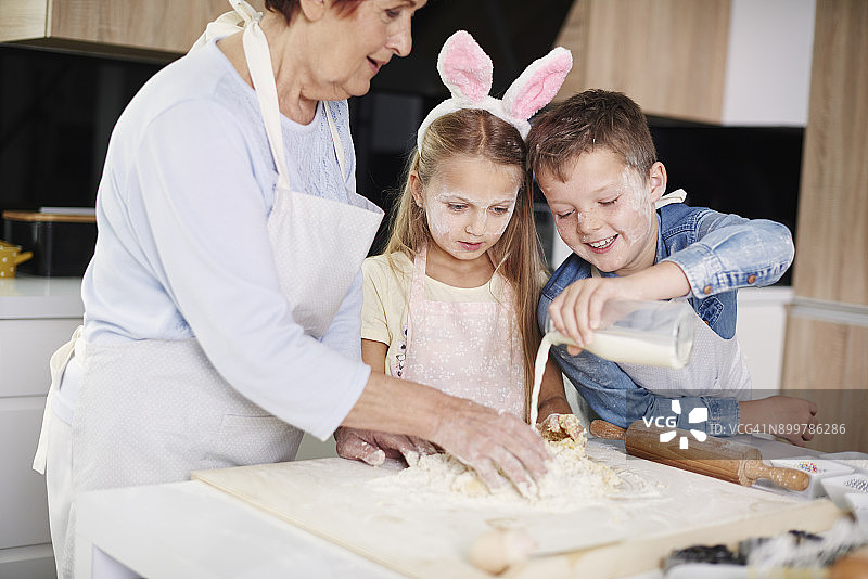 女孩和哥哥在厨房柜台帮助祖母复活节烘焙图片素材
