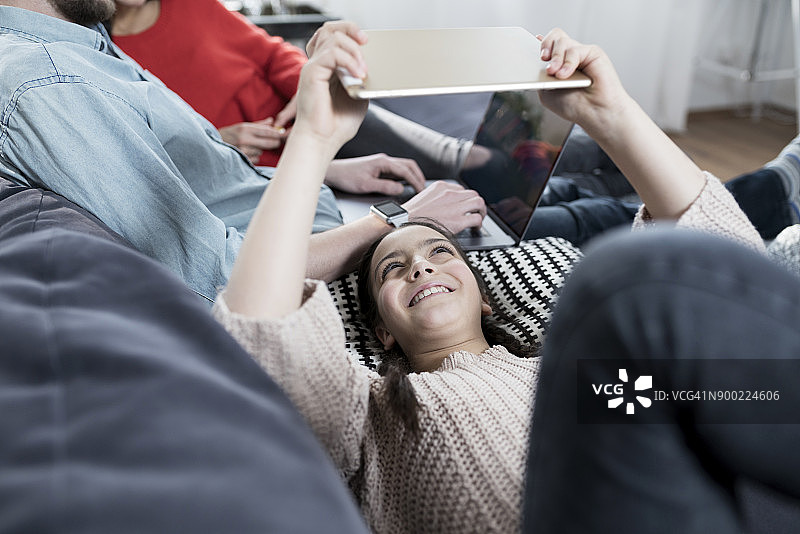 女孩和家人躺在沙发上拿着平板电脑图片素材