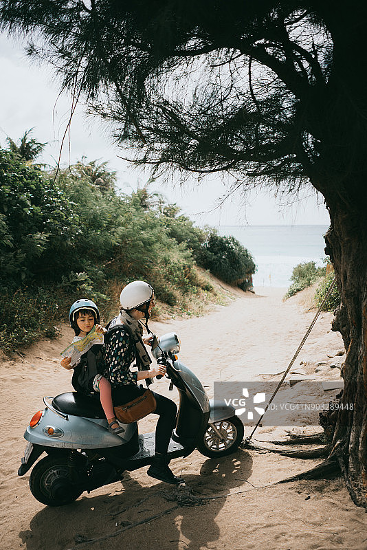 妈妈和孩子骑着滑板车去海滩图片素材