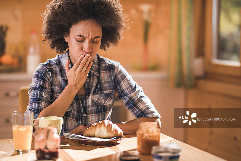 年轻的非洲裔美国妇女感到恶心在早餐时间在餐厅。图片素材