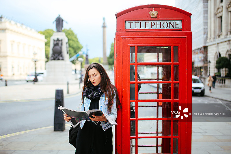 一名年轻女子站在伦敦街头看杂志图片素材