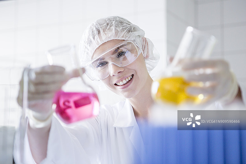 在实验室微笑的科学家举着两个盛满液体的烧杯图片素材