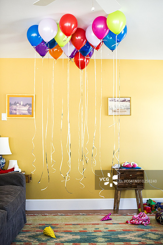 黄色墙壁的客厅里挂着一组用绳子系着的氦气球图片素材