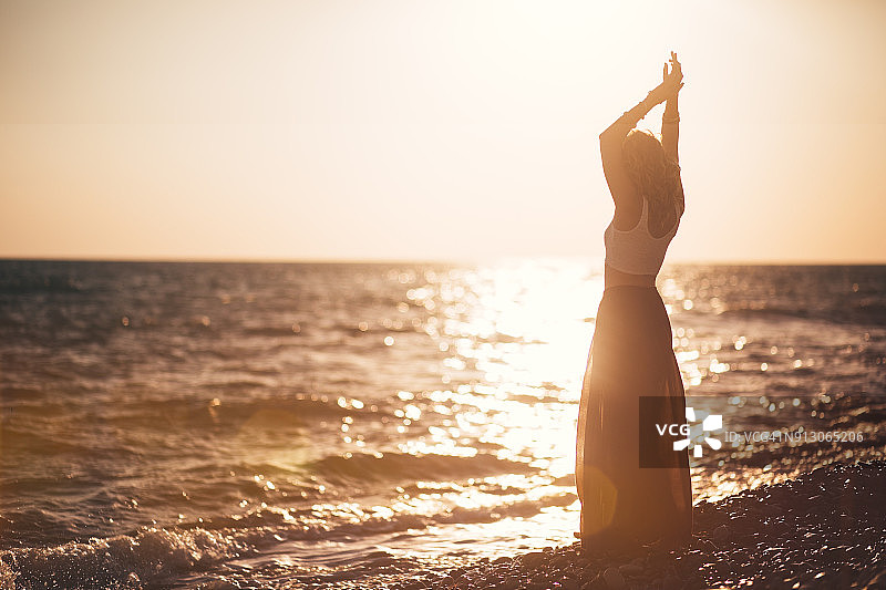 日落时分，嬉皮女人在海滩上放松图片素材