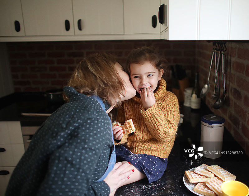 一位母亲在厨房里亲吻她的小女孩图片素材