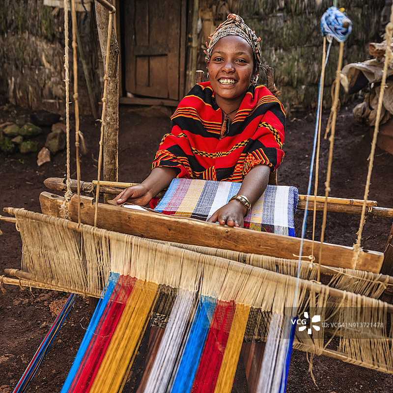 东非埃塞俄比亚，年轻的非洲妇女正在编织一条色彩鲜艳的围巾图片素材
