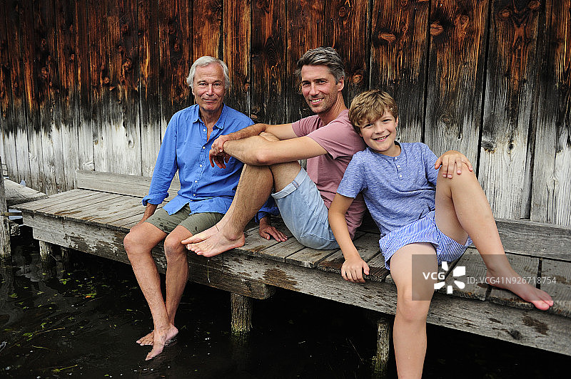 夏天，男孩和爷爷、爸爸一起坐在码头上图片素材