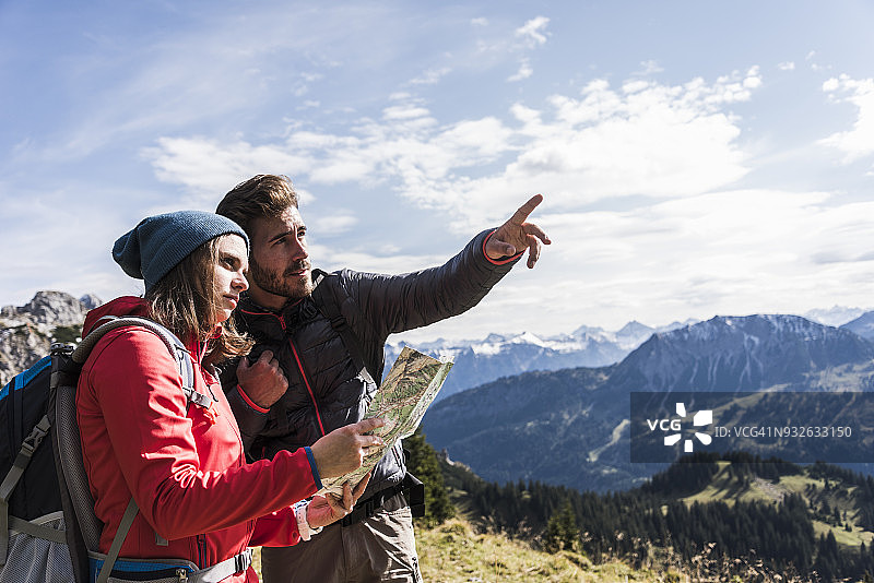 奥地利，蒂罗尔，一对年轻夫妇带着山景地图环顾四周图片素材