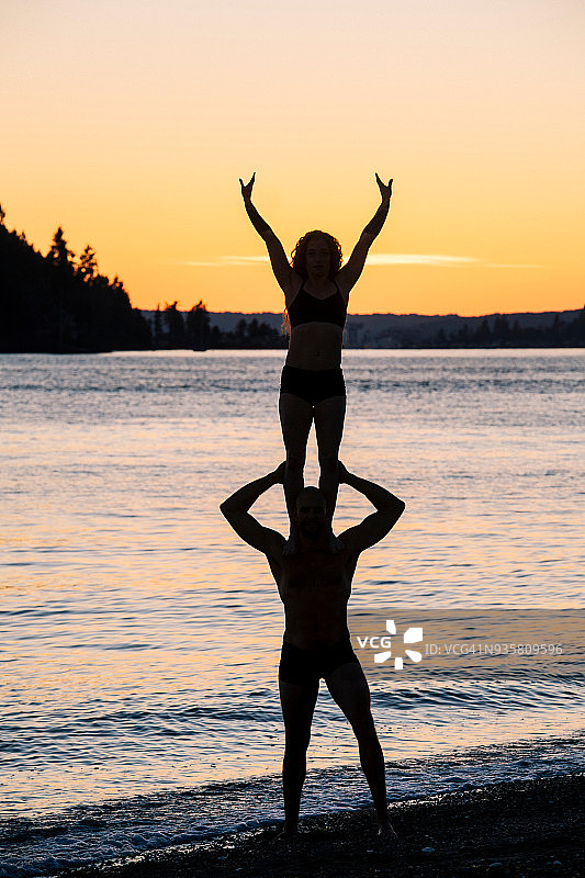日落时分，一对情侣在海滩上练习瑜伽图片素材