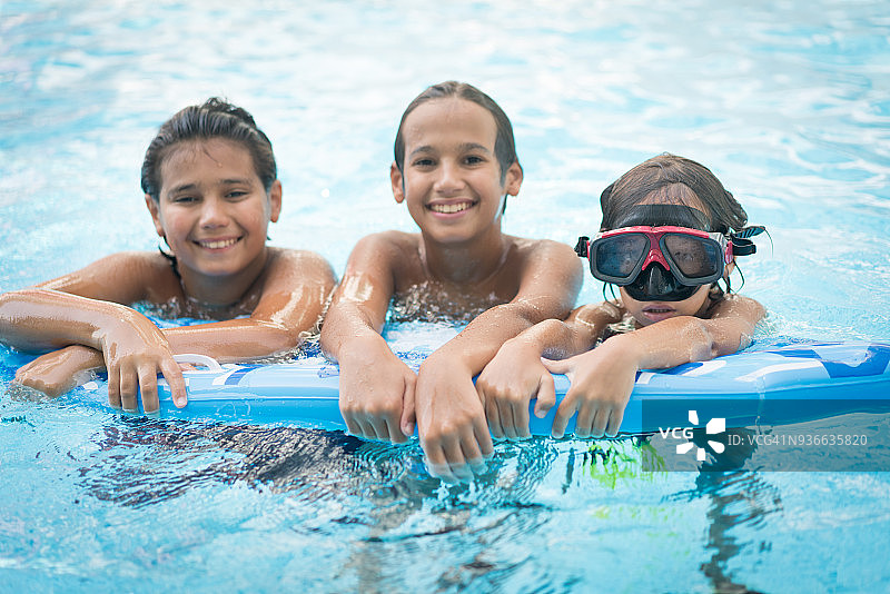 三个孩子在游泳池的水面上漂浮图片素材