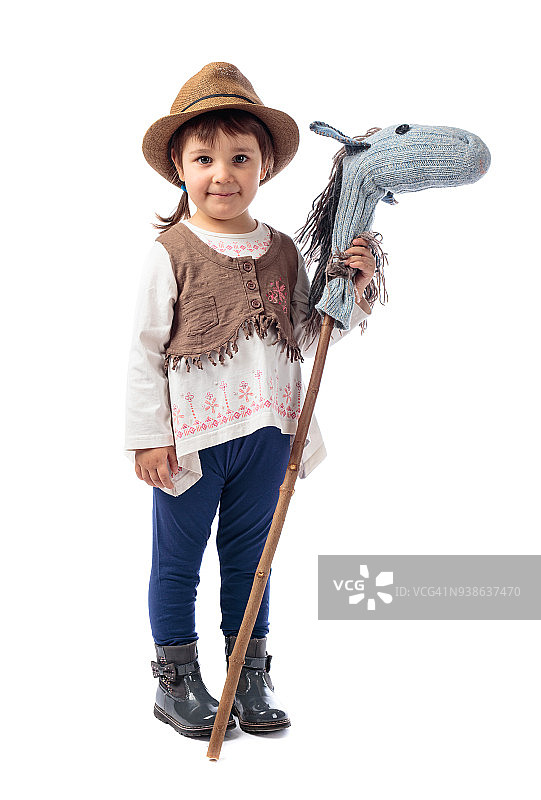 可爱的小女孩打扮得像个牛仔在玩自制的马。图片素材