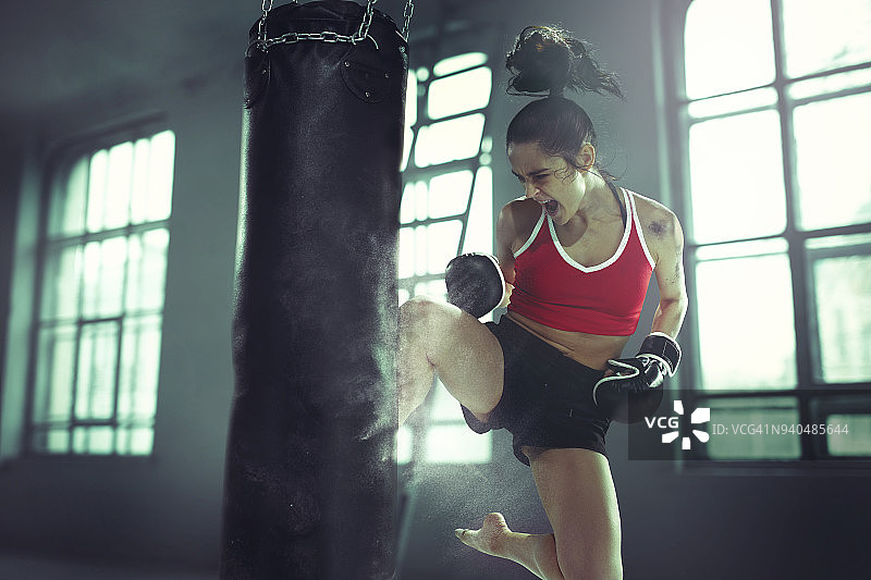 一个年轻女子在一个黑暗的老健身房拳击锻炼图片素材