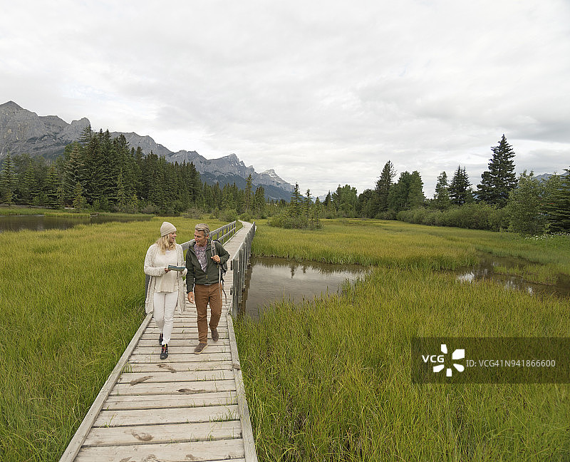 夫妇沿着木板路走过沼泽。图片素材