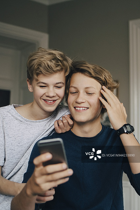 微笑的男性朋友在家里用智能手机图片素材
