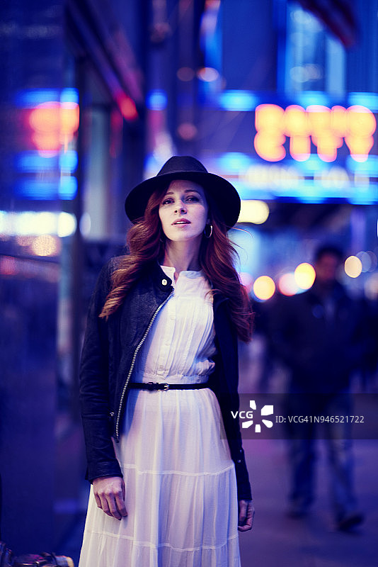 黄昏时分，身穿白衣、头戴白帽的年轻女子站在纽约无线电城外图片素材