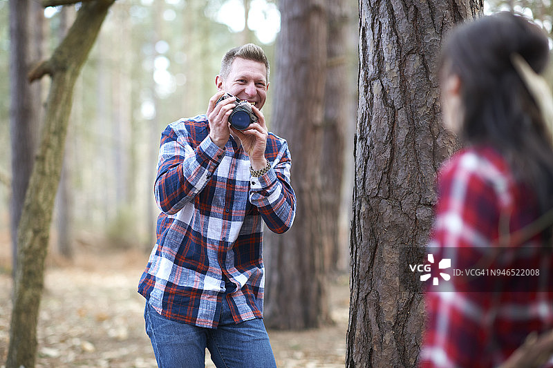 一名男子在树林里给他的女伴拍照图片素材