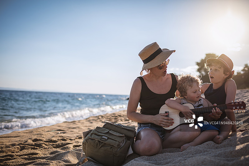 妈妈和她的孩子们在海滩上弹吉他图片素材
