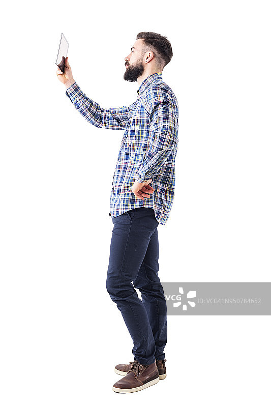 胡须浓密的年轻商人手持平板电脑的侧视图图片素材
