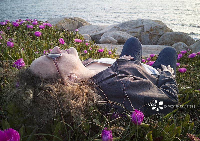 女人躺在长满鲜花的草地上图片素材