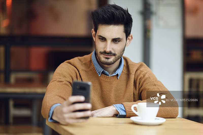 一个年轻人坐在咖啡店里用手机图片素材