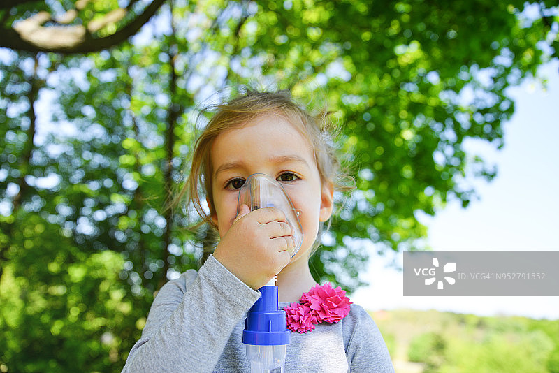 一个女孩在公园里使用哮喘吸入器图片素材