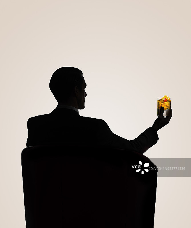 轮廓分明的男性坐在椅子上喝着威士忌图片素材