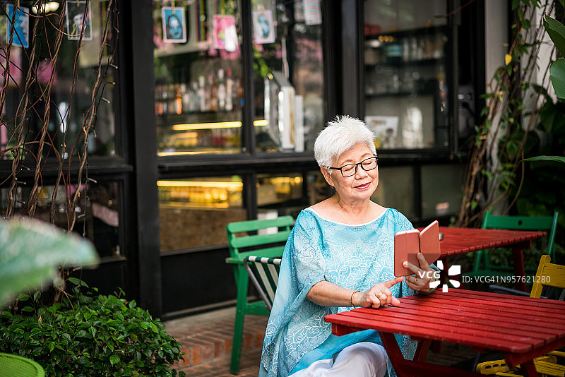一位年长的亚洲女性正在看她的智能手机图片素材