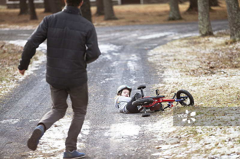 父亲朝儿子跑去的背影，儿子在路上从自行车上摔下来图片素材