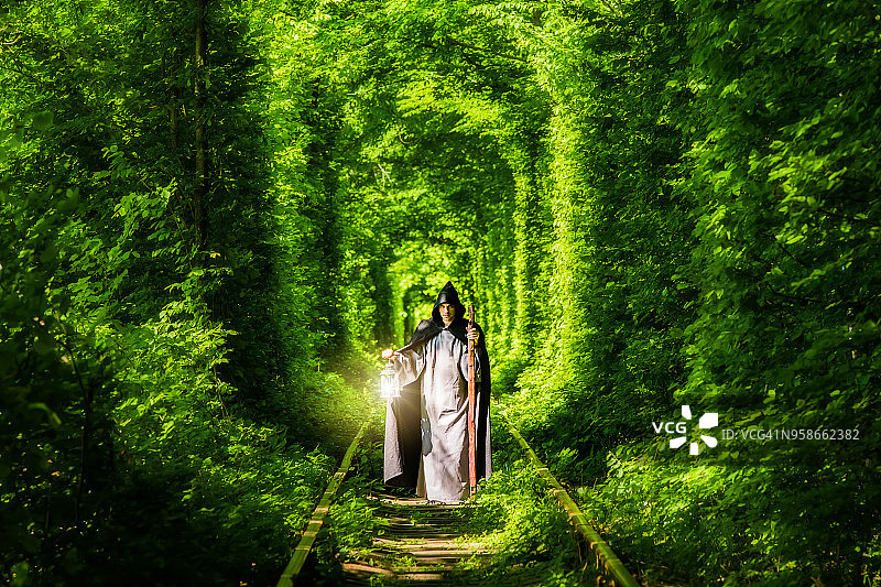 在绿色森林的隧道里提着灯笼的巫师图片素材