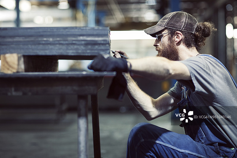 男性工人在工业钢板上工作的侧视图图片素材