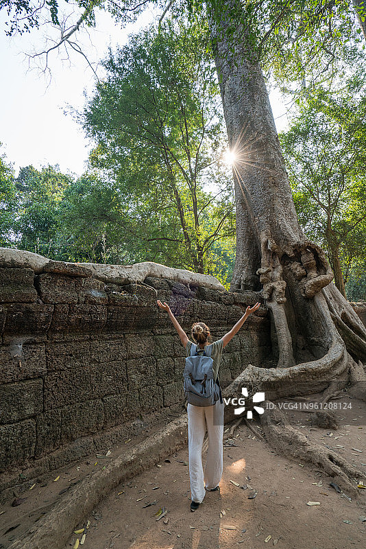 柬埔寨一座古庙前，一位年轻女子伸出双臂图片素材