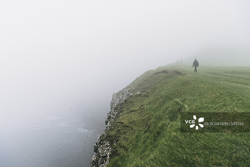 在大雾天气下的悬崖上的远足者的高角度视图图片素材