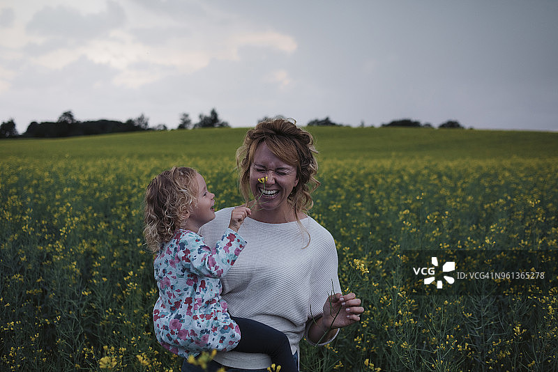 在天空的衬托下，女儿抚摸着母亲鼻子上的花朵图片素材