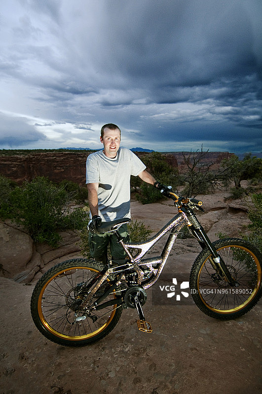 一个骑着自行车的人站在阴天的岩石上的肖像图片素材
