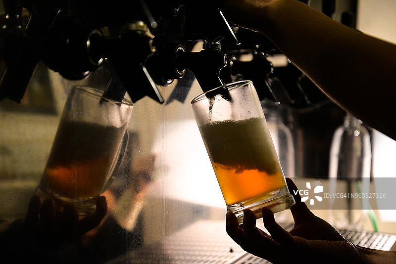 啤酒杯和手在水龙头上倒啤酒图片素材