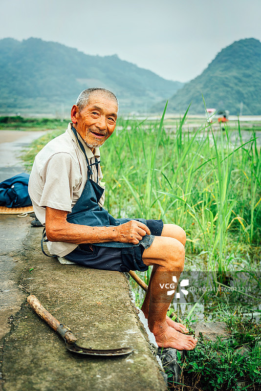 一位中国老农坐在稻田里图片素材