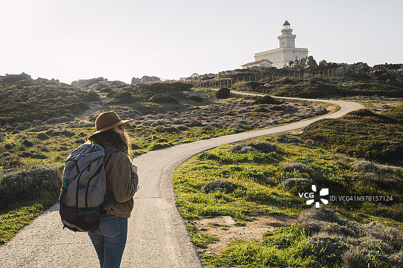 意大利，撒丁岛，一个女人徒步旅行走向灯塔图片素材