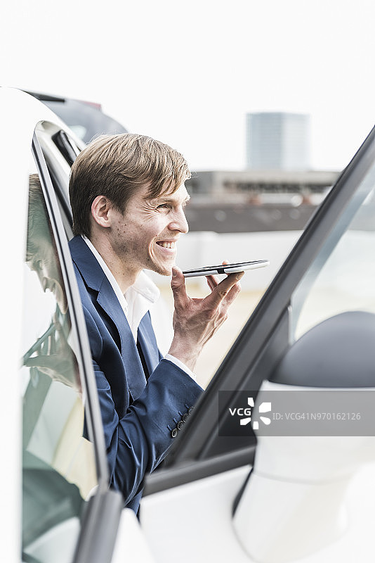 微笑的商人在车里使用智能手机图片素材