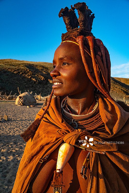 在纳米比亚Sesfontein附近的Puros村，身着传统服装的赤褐色、裸露乳房的辛巴妇女在傍晚的光线中向远处望去(模特释放)图片素材