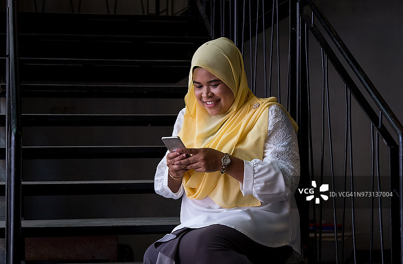 年轻的纱布女人坐着用手机图片素材