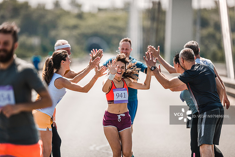 快乐的运动员在马拉松路上向他们的支持者致意。图片素材