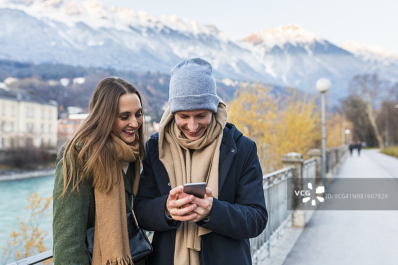 奥地利，因斯布鲁克，一对快乐的年轻夫妇看着手机图片素材