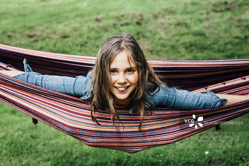 微笑的女孩躺在吊床上伸出舌头的肖像图片素材