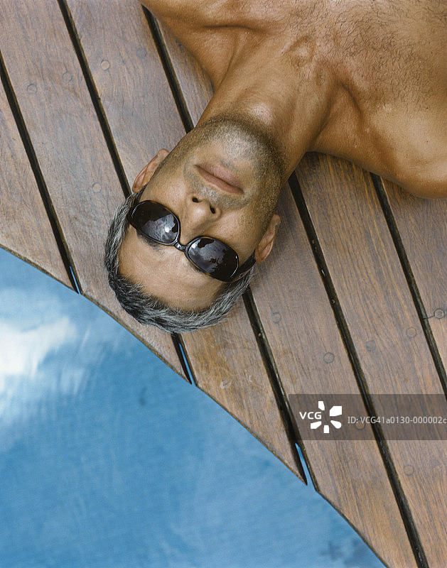 在游泳池附近晒太阳的男人图片素材