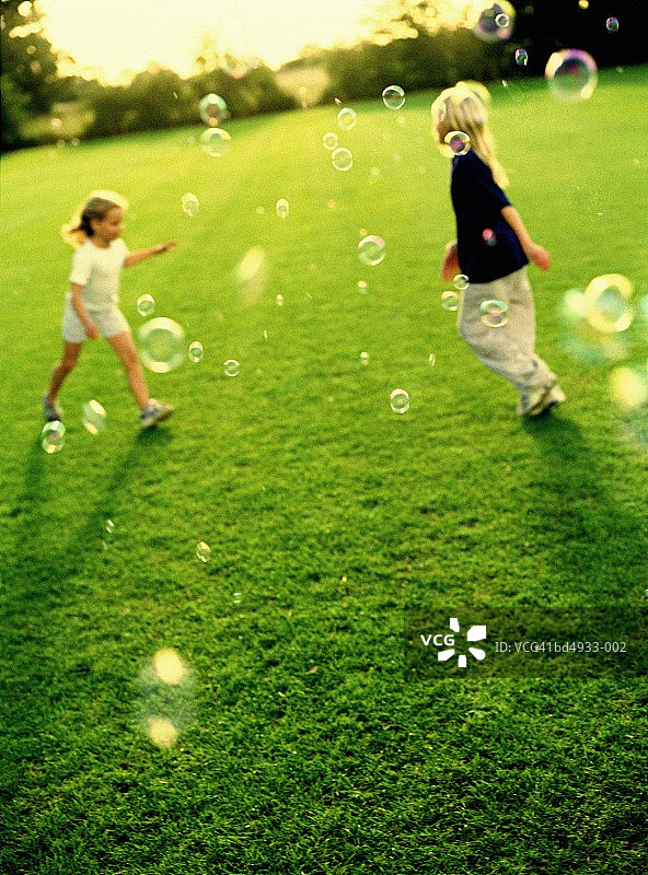 两个女孩(5-9)追逐泡沫图片素材