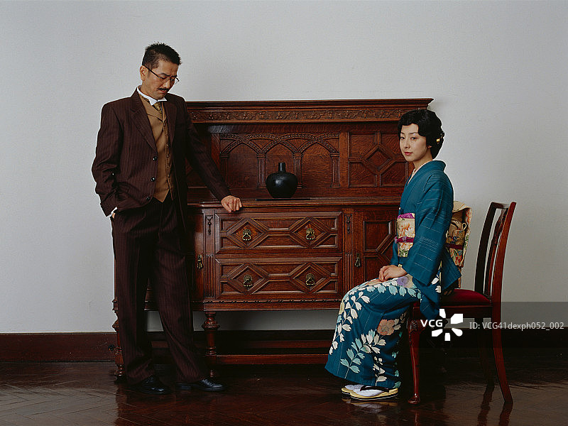 传统的日本夫妇，女人坐在椅子上，男人站着图片素材