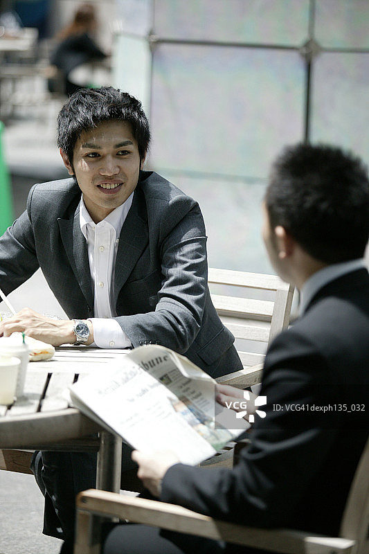 两个年轻的商人在一个户外咖啡馆喝咖啡图片素材